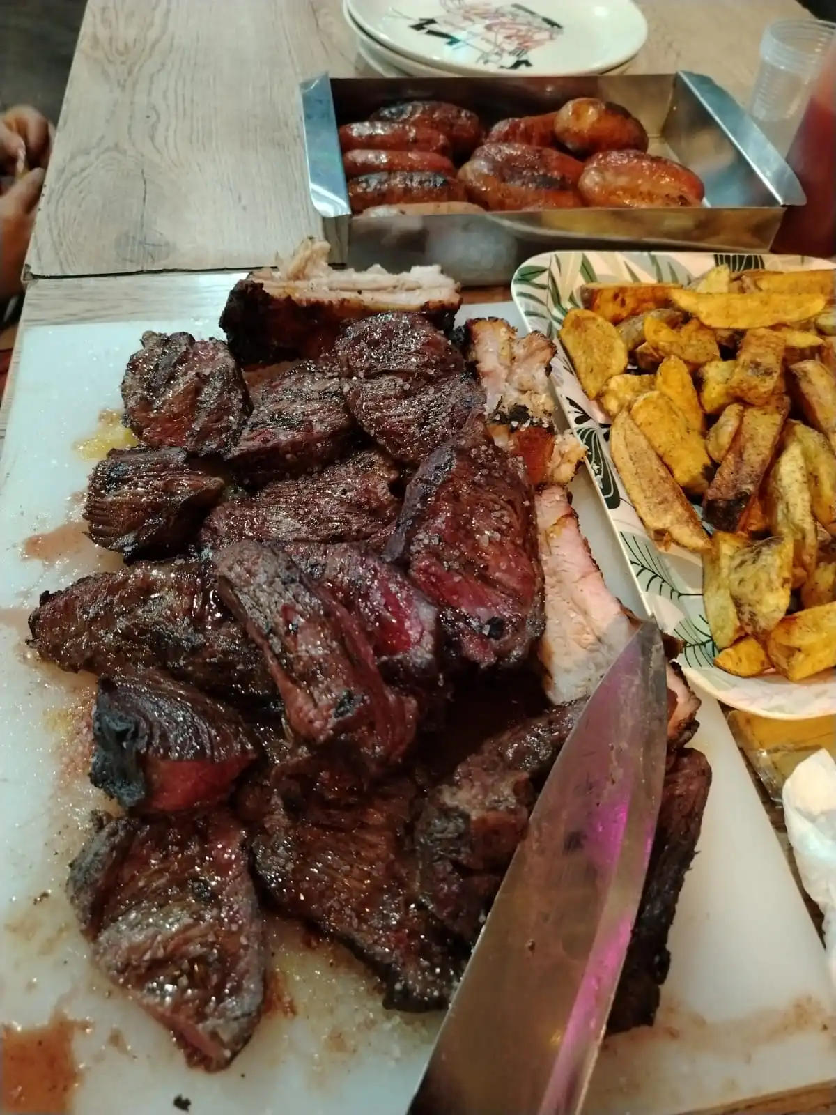 Cortes de carne a la parrilla servidos en tabla con papas rústicas